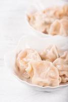 vers, heerlijk gekookt varkensvlees gyoza dumplings, jiaozi op witte achtergrond met sojasaus en eetstokjes, close-up, levensstijl. zelfgemaakte ontwerpconcept. foto