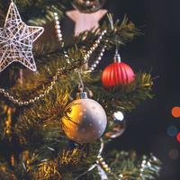 mooi kerstdecorconcept, kerstbal die aan de kerstboom hangt met sprankelende lichte vlek, wazige donkere zwarte achtergrond, macrodetail, close-up. foto