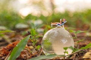 miniatuur mensen zonnebaden op kristallen bol in het park foto