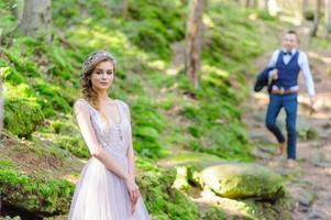 een aantrekkelijk pasgetrouwd stel, een gelukkig en vreugdevol moment. een man en een vrouw scheren en kussen in vakantiekleren. bohemien-stijl bruiloft cermonia in het bos in de frisse lucht. foto