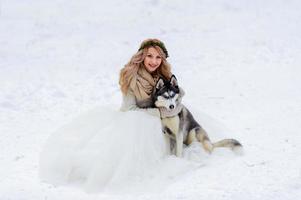 vrolijke pasgetrouwden lopen op het pad in het besneeuwde bos met twee Siberische honden. winterse bruiloft. kunstwerk. kopieer ruimte foto