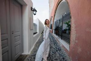 de mooie blonde haren jonge vrouwen bruid blauw in een bruiloft witte lange sexy jurk op santorini in griekenland foto