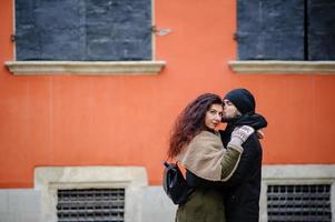 jonge gelukkige paar geliefden aan het begin van het liefdesverhaal - knappe man fluistert zachte kussen in het oor van de mooie vrouw - herfstmodeconcept met vriend en vriendin op een koude vintage gefilterde look foto