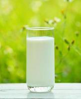 glas melk op witte tafel in de ochtend tuin