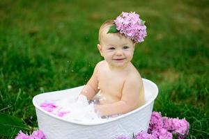 klein meisje baadt in een melkbad in het park. het meisje heeft plezier in de zomer. foto