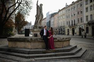 portret van mooie lachende liefde paar zitten in de buurt van fontein buiten in de stad. knappe jonge man en vrouw. foto