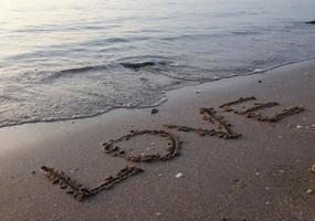 strand zeewater op het strand geschreven op zand, liefde foto