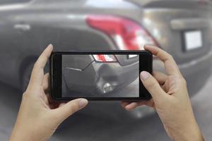 hand met smartphone maak een foto op de plaats van een auto-ongeluk, auto-ongeluk voor verzekering
