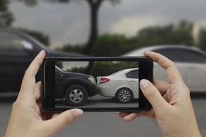 hand met smartphone maak een foto op de plaats van een auto-ongeluk, auto-ongeluk voor verzekering