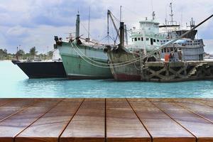 leeg houten tafelruimteplatform en boten op de zee en de luchtachtergrond voor montage van productweergave, houten tafel voor productplaatsing foto