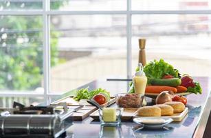 gezonde voeding, biologische rauwe groente en gebruiksvoorwerpen om op tafel te koken in de moderne keuken foto