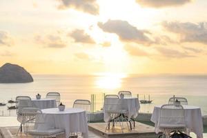 gezellig en romantisch café met tafel en stoelen op het dak met uitzicht op zee en de zonsondergang foto