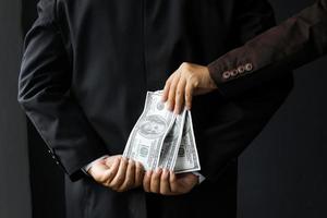 corruptie en omkoping, zakenman ontvangt geld van een andere zakenman van achteren om contract te sluiten