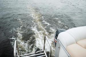 de achtersteven van een motorboot met een bubbelend spoor foto