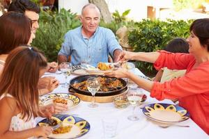 familie van meerdere generaties die samen van maaltijd op terras genieten foto