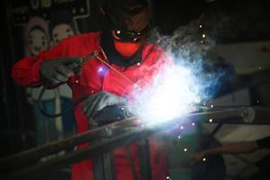 lasser gebruikte slijpsteen op staal in fabriek met vonken, lasproces in de industriële werkplaats, handen met instrument in frame. foto