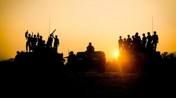 silhouetten van legersoldaten in de mist tegen een zonsondergang, mariniersteam in actie, omringd door vuur en rook, schietend met aanvalsgeweer en machinegeweer, aanvallende vijand foto