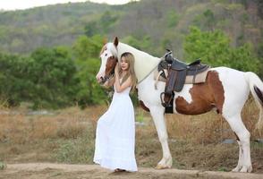 jonge vrouw met haar paard in avondzonsonderganglicht. buitenfotografie met fotomodel meisje. levensstijl stemming foto