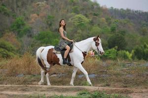 jonge vrouw met haar paard in avondzonsonderganglicht. buitenfotografie met fotomodel meisje. levensstijl stemming foto