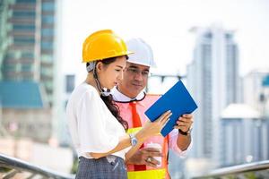 de ingenieur en zakenvrouw die op het klembord controleren bij de bouw van de bouwplaats. het concept van engineering, constructie, stadsleven en toekomst. foto