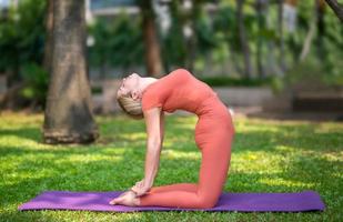 volledige lengte van een vrouw die yoga uitoefent op de mat in het park foto