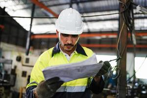 voorman of arbeider werkt op fabriekslocatie controleer machine of producten op locatie. ingenieur of technicus die materiaal of machine op de fabriek controleert. industrieel en fabriek. foto