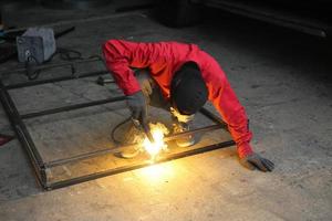 lasser gebruikte slijpsteen op staal in fabriek met vonken, lasproces in de industriële werkplaats, handen met instrument in frame. foto