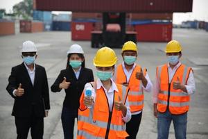 groep industriearbeiders controleert het laden van containers in de containerterminal, tijdens covid-19-controle. foto