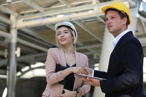 de ingenieur en zakenvrouw die op het klembord controleren bij de bouw van de bouwplaats. het concept van engineering, constructie, stadsleven en toekomst. foto