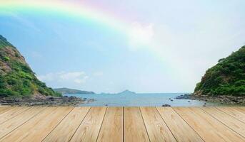leeg houten tafelblad en uitzicht op tropisch strand met raibow over zee achtergrond foto