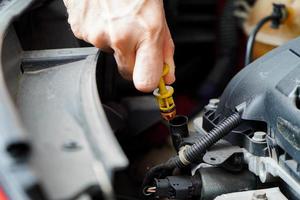 automonteur die het oliepeil in de automotor controleert, inspecteert de peilstok van het motorwaterpeil; foto