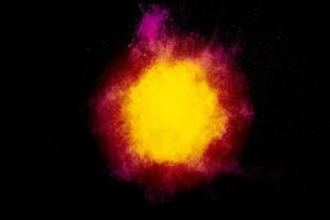 rood geel poeder explosie wolk op zwarte achtergrond. bevriezen beweging van rood gele kleur stofdeeltjes spatten. foto