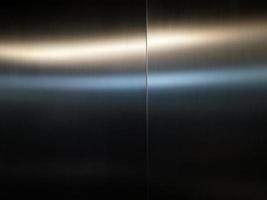 roestvrijstalen grote plaat met licht dat het oppervlak raakt voor achtergrond, in passagierslift, reflectie van licht op een glanzende metalen textuur, roestvrijstalen achtergrond. foto