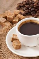 close-up weergave van een kopje koffie, bruine suiker en koffiebonen