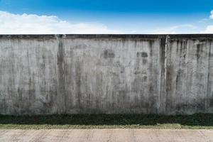 oude gebarsten grijze cement of betonnen muur met blauwe lucht als achtergrond. grunge gepleisterd stucwerk getextureerde achtergrond. foto
