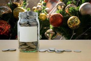 geld in de glazen fles met versierde kerstboom achtergrondvervaging foto