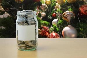 geld in de glazen fles met versierde kerstboom achtergrondvervaging foto