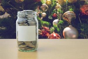 geld in de glazen fles met versierde kerstboom achtergrondvervaging foto