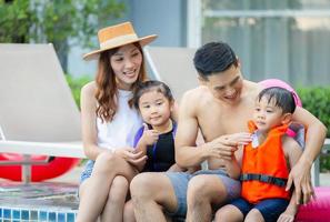 jonge Aziatische familie ontspannen in het zwembad. familie op vakantie met plezier bij het zwembad, geluk levensstijl concepten foto