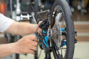 fietsenmaker repareert vouwfiets in werkplaats. achterderailleur, cassettetandwiel afstellen. fietsonderhoud en reparatieconcept foto