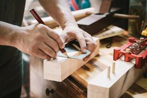 timmerman die een rood potlood gebruikt om een lijn op hout te trekken in de werkplaats., doe-het-zelfmaker en houtbewerkingsconcept. selectieve focus foto