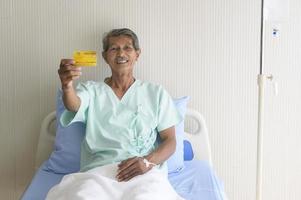 een Aziatische senior geduldige man toont creditcard in het ziekenhuis foto