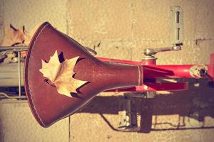 herfstblad over het zadel van een oude fiets. vintage-stijl. concept aankomst herfst. horizontaal beeld. foto