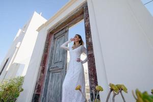 de mooie blonde haren jonge vrouwen bruid blauw in een bruiloft witte lange sexy jurk op santorini in griekenland foto