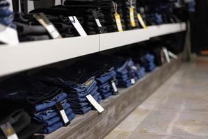 stapel blauwe en zwarte jeans in een winkel. foto