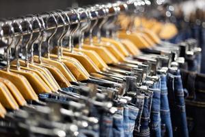 rij opgehangen blauwe en zwarte jeans op hangers in een winkel. foto