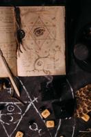 open oud boek met magische spreuken, runen, zwarte kaarsen op heksentafel. occult, esoterisch, waarzeggerij en wicca concept. foto