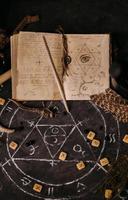 open oud boek met magische spreuken, runen, zwarte kaarsen op heksentafel. occult, esoterisch, waarzeggerij en wicca concept. foto