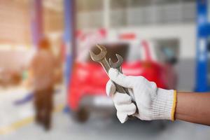 automonteur met moersleutel bij de autoreparatiegarage foto