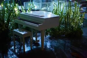 stijlvolle witte piano versierde staat 's avonds op straat. muziekinstrument voor de pianist. buiten huwelijksceremonie foto